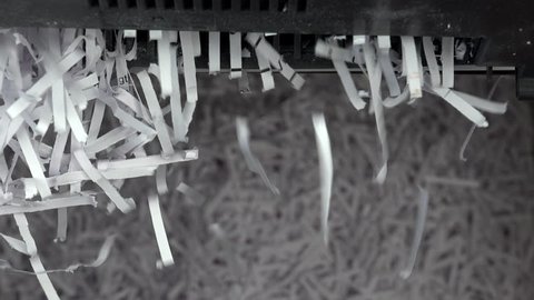 Paper document cut into strips by sharp blades, close up, falls onto pile of shredded paper strips background. 4K UHD, 3840x2160