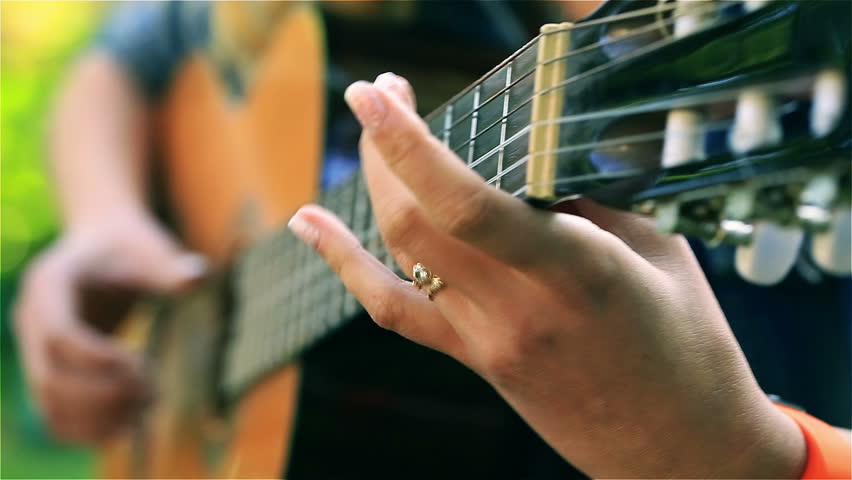 Happy girl playing on guitar in the park, steadycam shot
