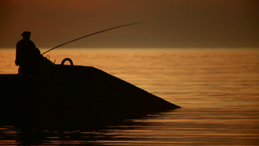 Silhouette of Fisherman at sunset. Past the floating fishing boat