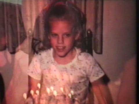 A cute little blond girl blows out the candles on her birthday cake as she celebrates turning ten years old.
