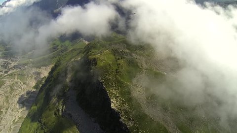 View of a green mountain landscape, clouds floating above mountains, POV