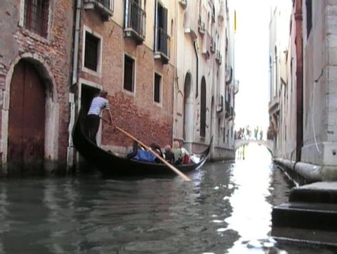 gondola passing along narrow canal with bridge