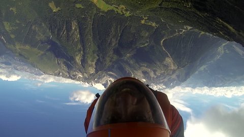 A base jumper in a wingsuit gliding down over a mountain landscape, POV