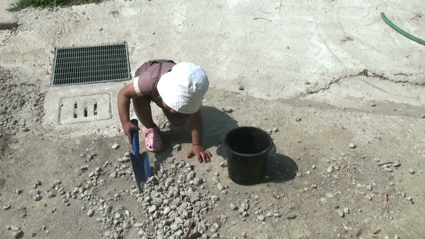 Digging with a shovel. Little girl is playing in the garden