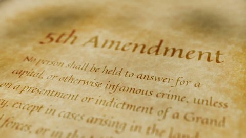 Scrolling text on an old paper background of the contents of the 5th amendment to the United States Constitution that protects citizens against unfair treatment in legal processes.