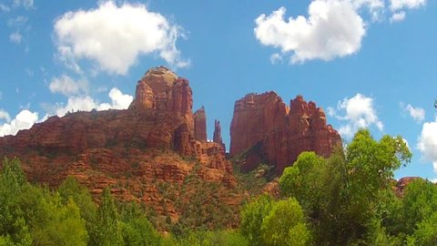 Time lapse fast motion shot of wispy white clouds passing over Cathedral Rock in Sedona Arizona. White puffy clouds cast moving shadows on the colorful red rock formation below.