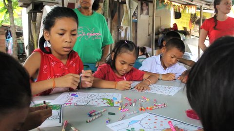BANGKOK, THAILAND, SEPTEMBER 2014: A group of cute Asian kids have fun coloring during an English lesson in the slums of Bangkok, Thailand.