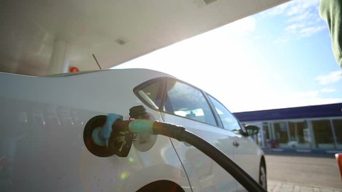 A man fills a white car quality biofuels at sunrise