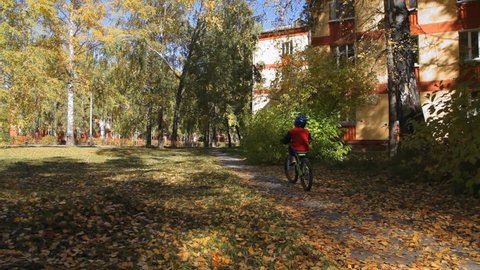 boy riding a bike on the street in autumn