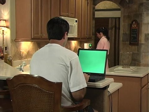 Couple in kitchen with green-screen laptop
