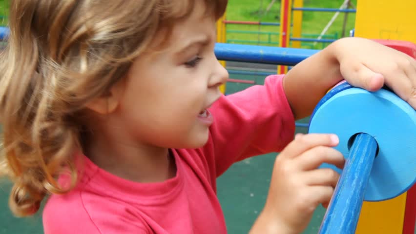 little girl moves on one hand on another small circles on pipe on playground 