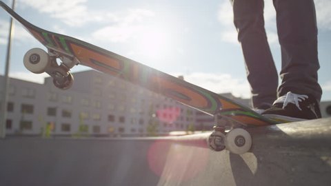 SLOW MOTION CLOSE UP: Skateboarder starts cruising down the ramp