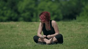 beautiful redhead woman relaxes sitting in a meadow,park
