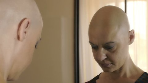 sad woman suffering from cancer at the mirror thinking: loneliness, fear,