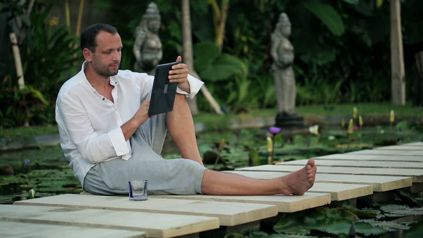 young man with tablet in the exotic garden
