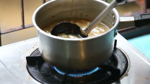 stirred ladle chicken with noodles and potatoes cold soup in a small saucepan on the gas stove near the window