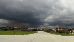 A car ride down road in residential suburban neighborhood looking at trees, clouds, houses and landscape - Travel and leisure concept