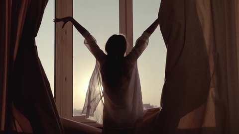 Woman in the morning. Attractive sexy woman with slender body opens curtains on big window and let the light in the room and having a perfect cozy morning. Slow motion 