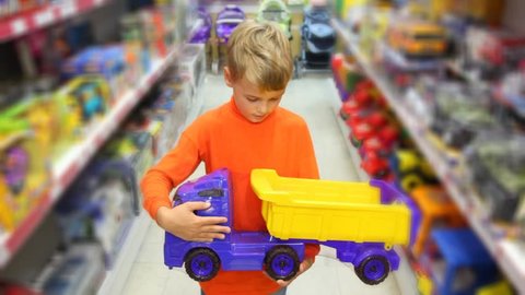 smiling caucasian boy with toy auto truck in supermarket 
