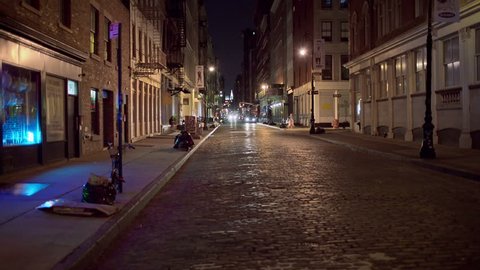 NEW YORK - AUG 1, 2014: desolate dark SoHo cobblestone street at night with Chrysler Building in background. SoHo is a neighborhood south of Houston Street in Manhattan, NYC.