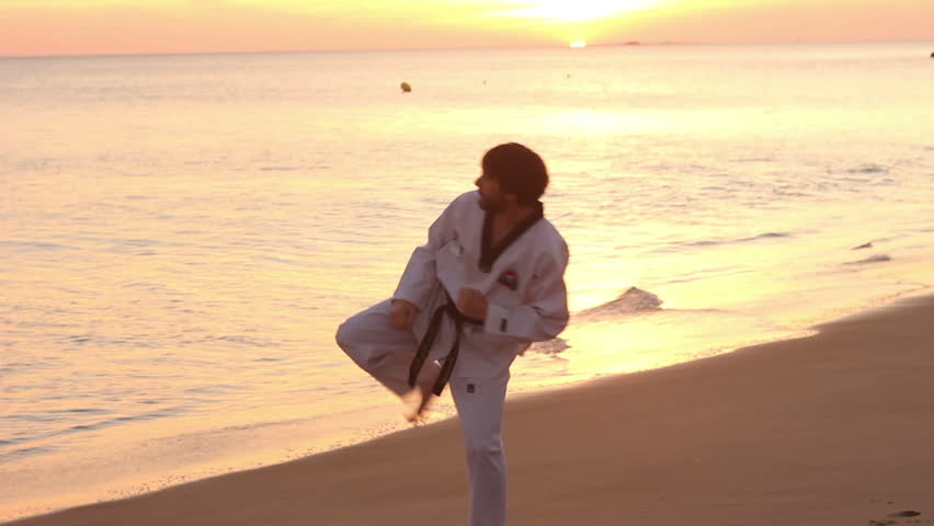 Silhouette of sport student exercising martial arts in beach. Panoramic skyline view.
