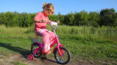 little girl treadling stopped bicycle, boy rides to her and pushes  Stock Video