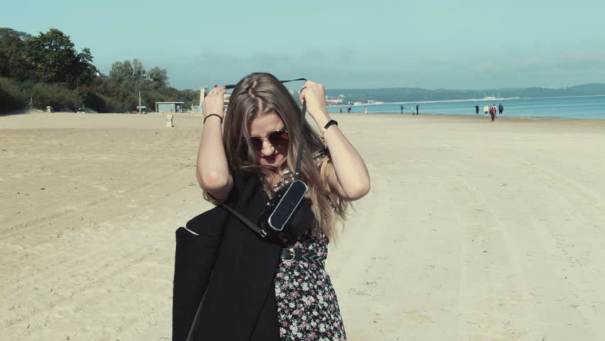Fashion portrait of woman in coat walking at the beach in autumn season.