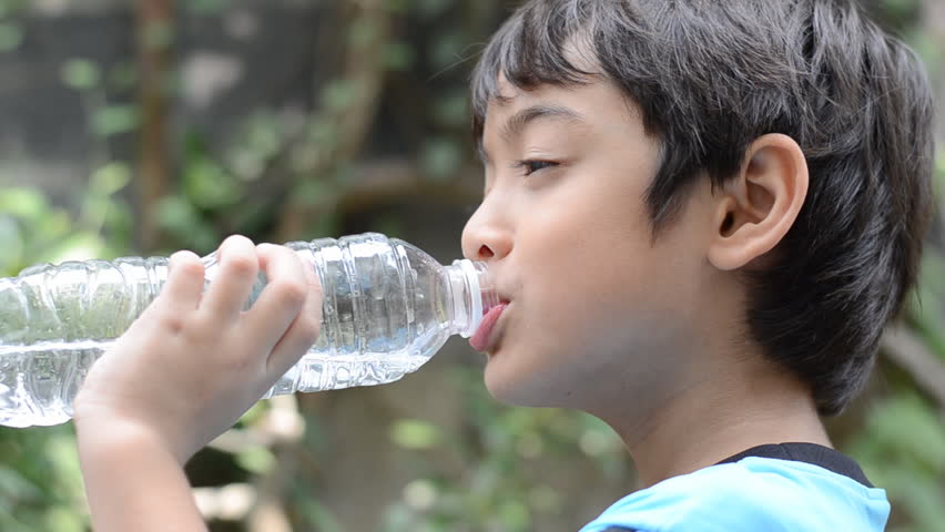 little boy drinks water from a bottle after excercise