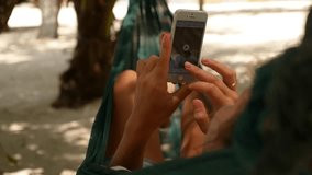Female Looking through Photos and Video on Smartphone in Beach Hammock during Vacation in Thailand. Koh Phangan. HD, 1920x1080.