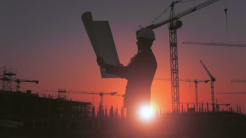 Steadicam shot of skyline and cranes with Asian construction/ executive/ architect/ engineer consultant discussing blue print of new urban development with caucasian construction executive at sunset.