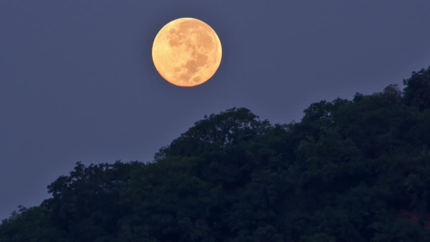large moon sets over the mountain