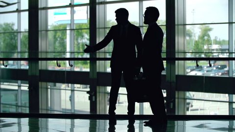 Silhouettes of two businessmen greeting each other with a handshake