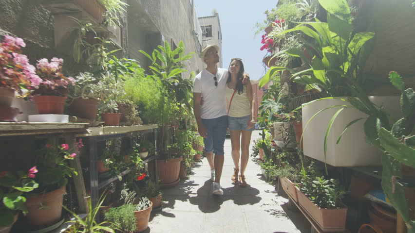 Attractive couple walking through narrow city alley with lots of plants