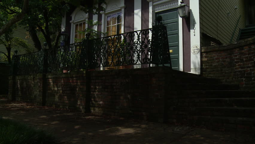 Beautiful old pre-Civil War house in Vicksburg, Mississippi with iron and brick fence. Camera tilts up.