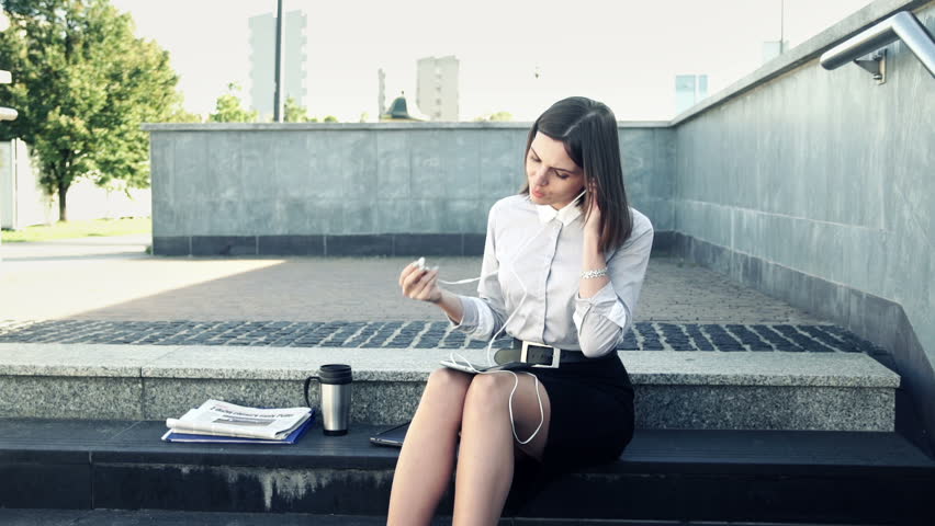Businesswoman listening to music on smartphone on stairs in the city
