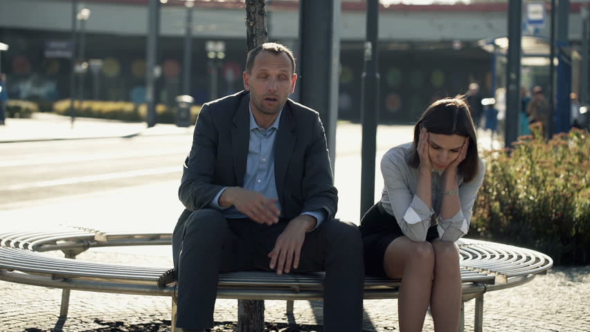 Sad, overwhelmed business people sitting on bench in the city
