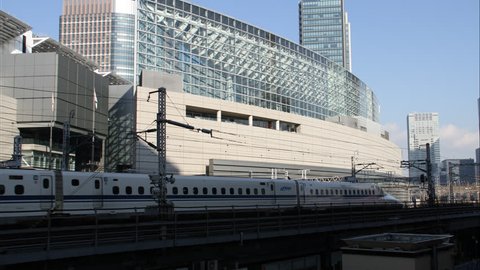 Commuter train traveling from left to right across frame, large building in background