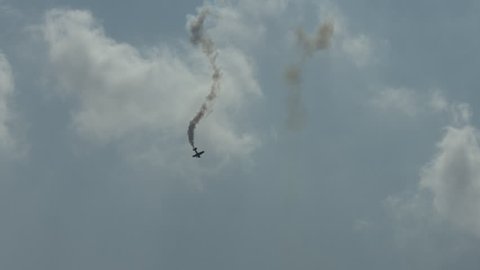 Jet Waco, a jet-powered biplane, performs aerobatics, spinning downwards and leaving smoke trails.  Recorded in 4K, ultra high definition.