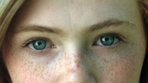 A CloseUp Of A Young Woman's Eyes, She Stares Into Camera, Then Her Eyes Brighten As She Smiles