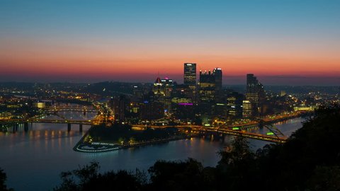 (Time-lapse) Morning twilight transitions to sunrise over Pittsburgh, Pennsylvania including the skyline, bridges, and Point State Park at the confluence of the Allegheny and Monongahela Rivers.