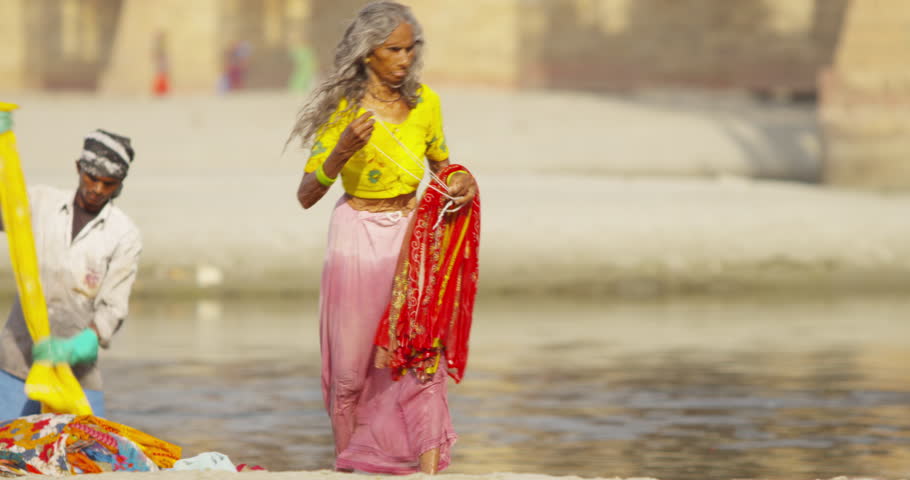 AGRA - April 7, 2014: Dhobi Ghat (laundry by hand) people are hard at work using the Yamuna to wash traditional Indian garments. Old woman drying off a piece of her garment. | Shutterstock HD Video #7618429
