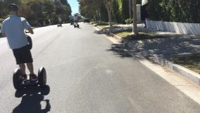 Man and group ride segways down a street