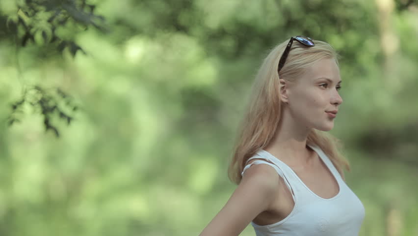 Shy young girl in a white t-shirt standing in the water of the pond and smiling