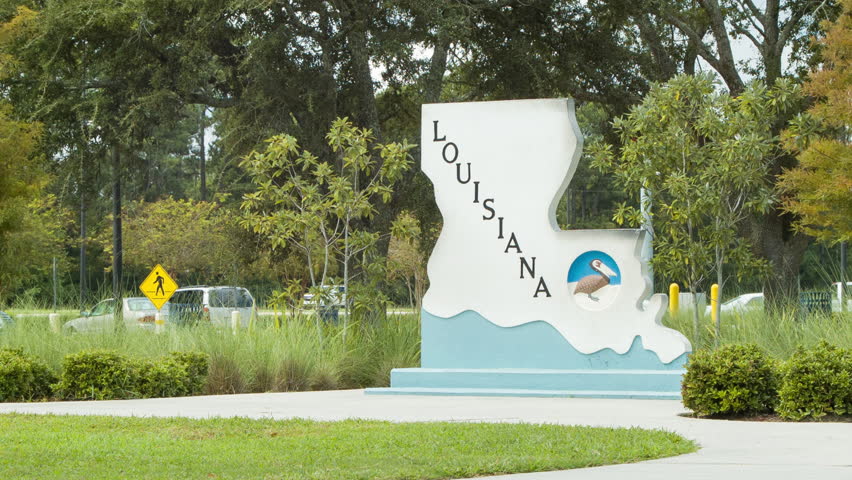 Louisiana Welcome Center on Interstate 10 Medium Shot with People Walking in the Backgrounds featuring Signage, Green Grass and Trees on a Sunny Day.