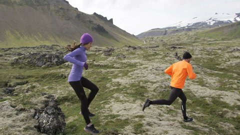 Trail runner man and woman running cross-country run training outside for marathon jumoing. Jogging male athlete working out as part of healthy lifestyle. From Snaefellsnes, Iceland. RED EPIC, 120 FPS