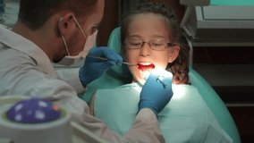 Dentist carry out routine inspection of the mouth of a little girl close-up video