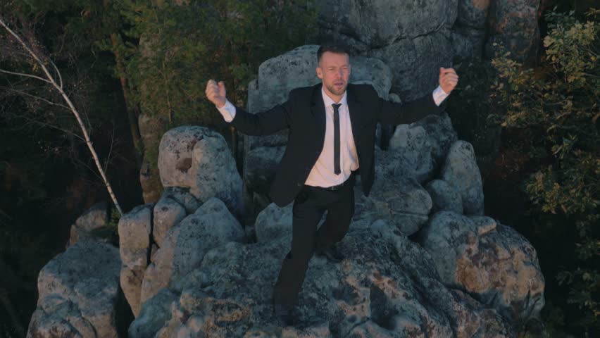 Young businessman on a rock overlooking autumn forest 