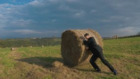 Businessman pushing hay bale