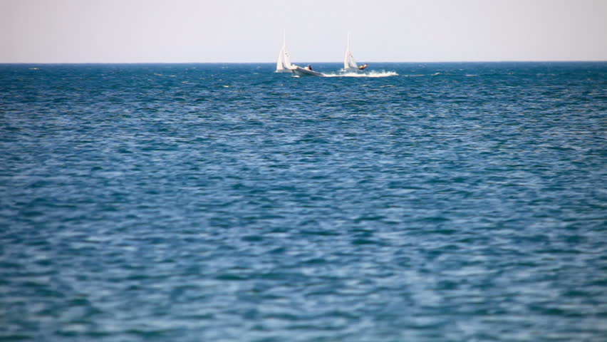 On the blue sea sailing several boats with white sails