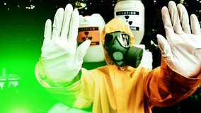 Dangerous radiating ; Chemist in protective clothing with gas mask gives a warning sign, fly cam video clip